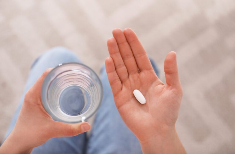 Young woman with abortion pill and glass of water, top view